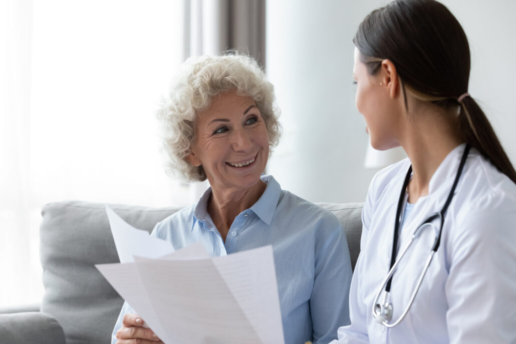 Young nurse and elderly woman patient talking about treatment plan